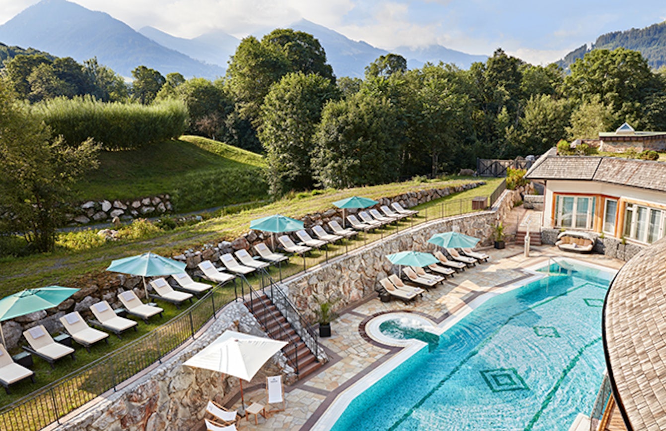 A hotel with a beautiful pool in a green landscape.