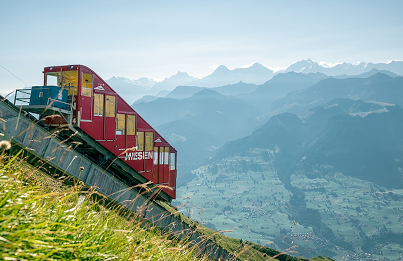 Funicular railway with the inscription “Niesen” with mountain panorama in the background.