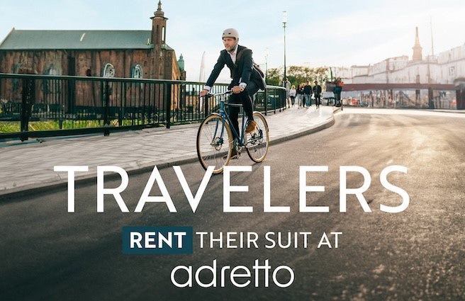 A cyclist rides on the road in a suit.